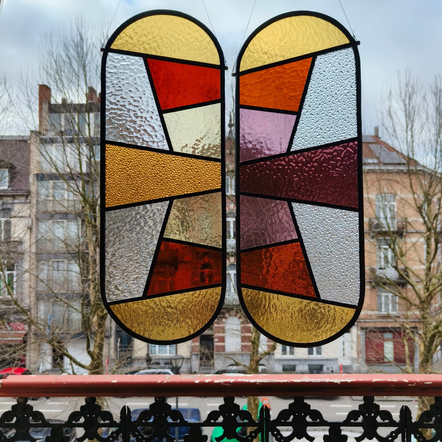 Pair of stainedglass windows in warm pinks, purples and yellows with some transparant structures.