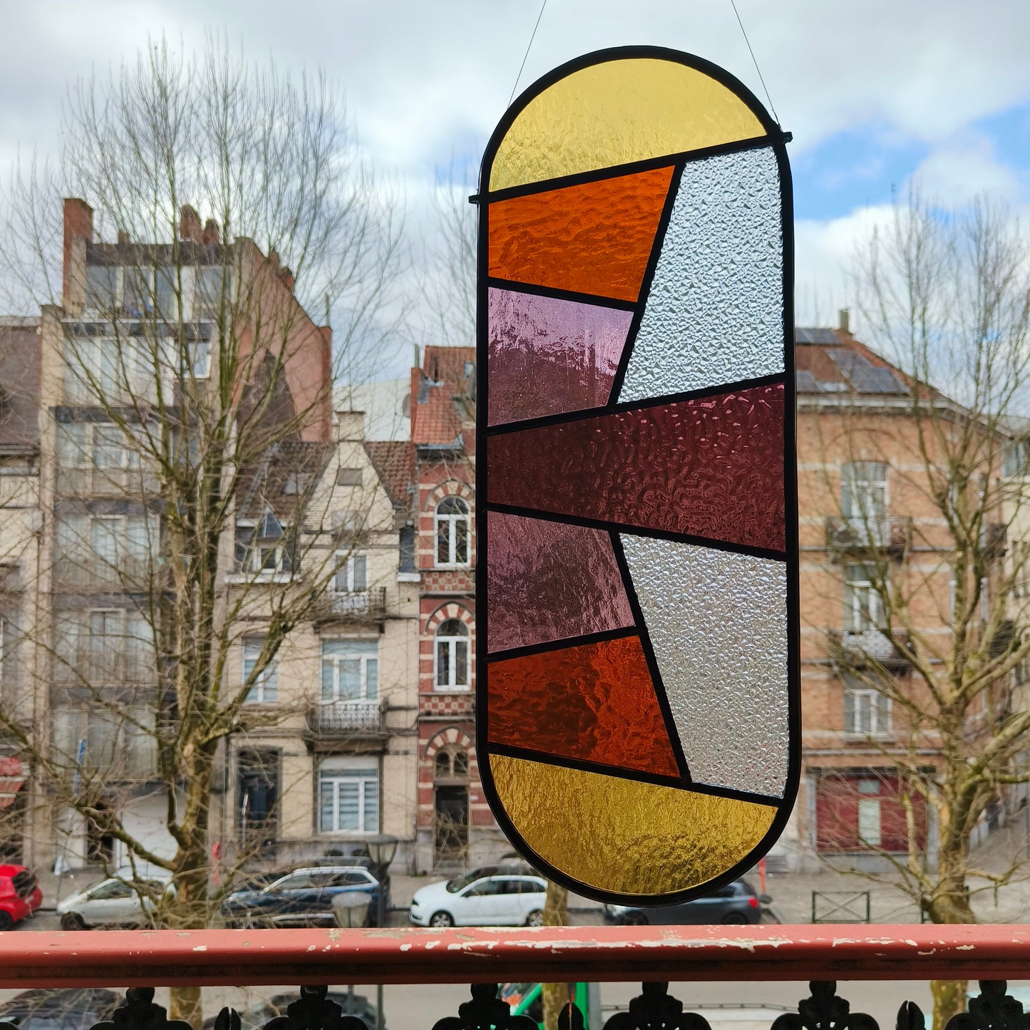 Stained glass window in warm pinks, purples and yellows with some amber glass.